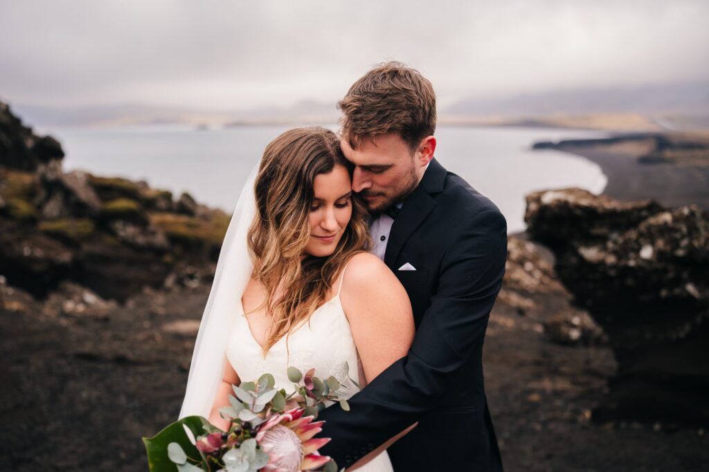 Couple stands against a breathtaking backdrop of majestic mountains and a serene ocean, capturing the essence of their epic elopement in Iceland