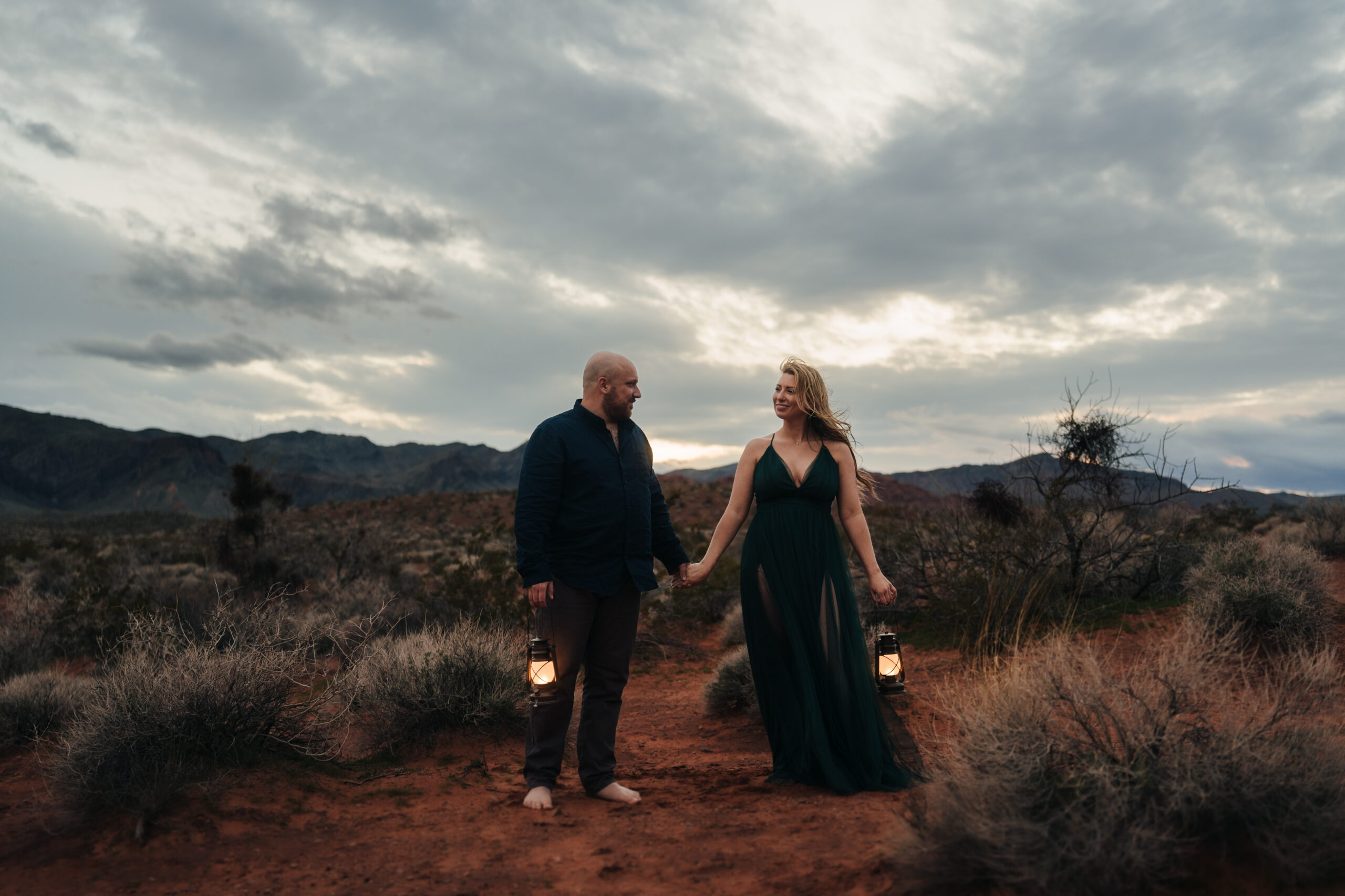 Couple walking while holding hands happily looking at each other during their engagement photo session at Valley of Fire while Photo taken by John Bognot Photography.
