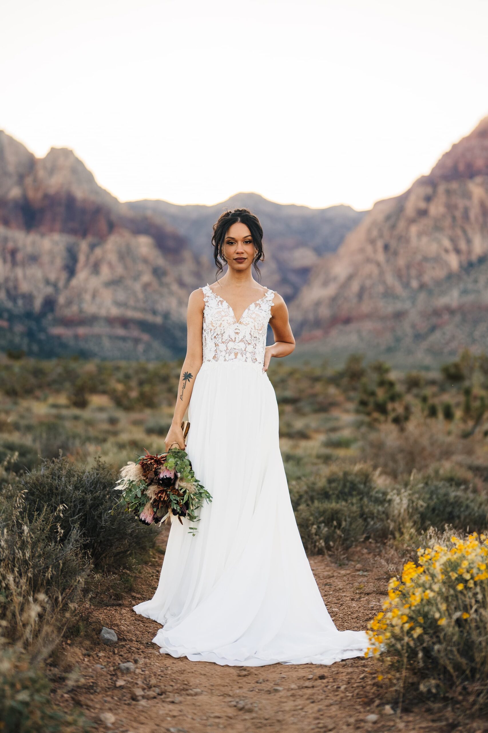 Bride wearing a beautiful wedding dress and holding a bouquet of flowers during her elopement in red rock canyon at Las vegas.