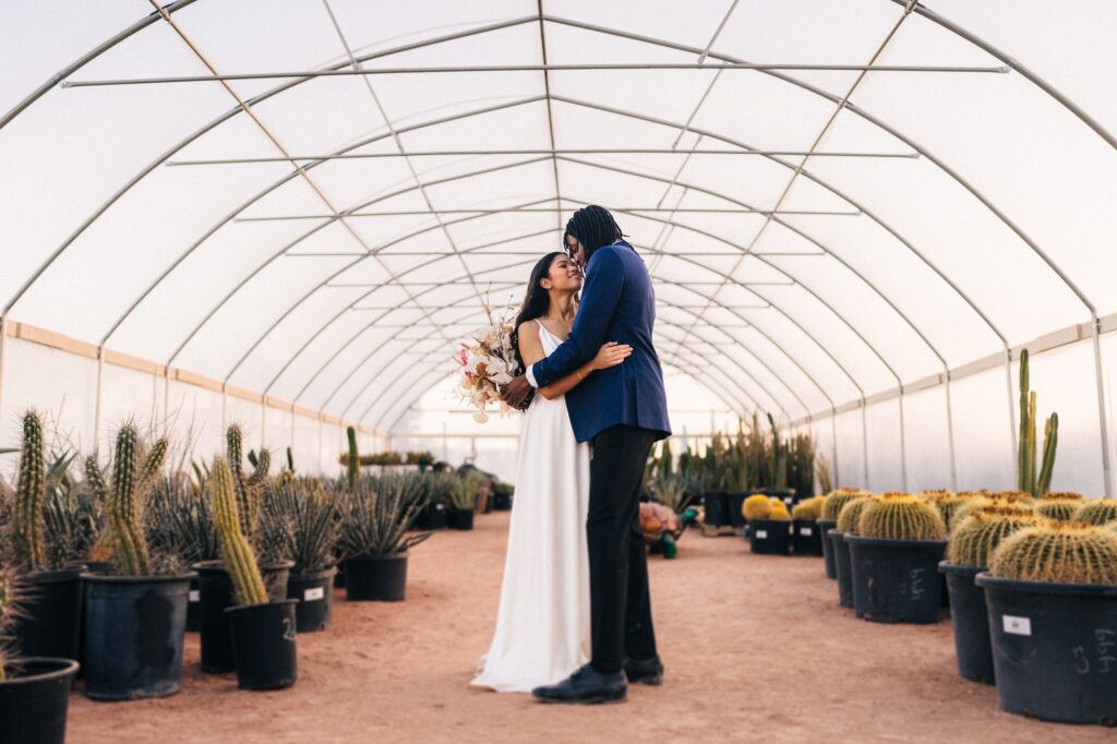 a couple holding each other during their elopement at Cactus Joe's greenhouse.
