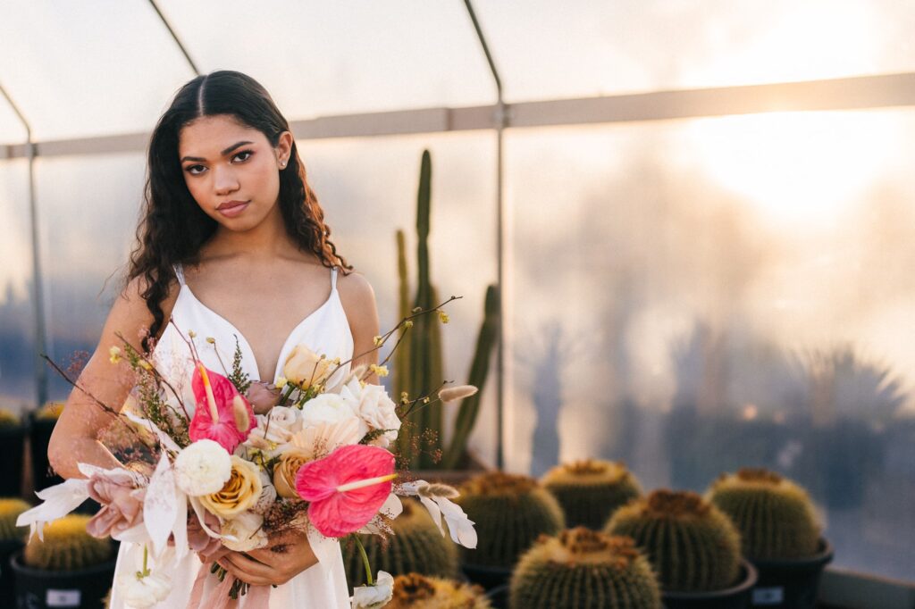 Bride holding her beautiful bouquet of flowers inside the greenhouse at Cactus Joe's.