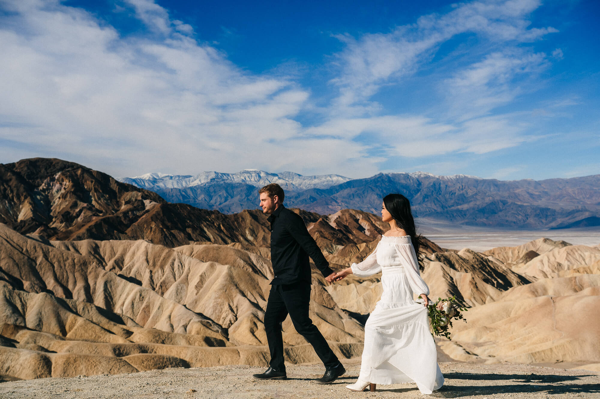 Couple walking hand in hand at zabriskie point in Death Valley National Park during their elopement.