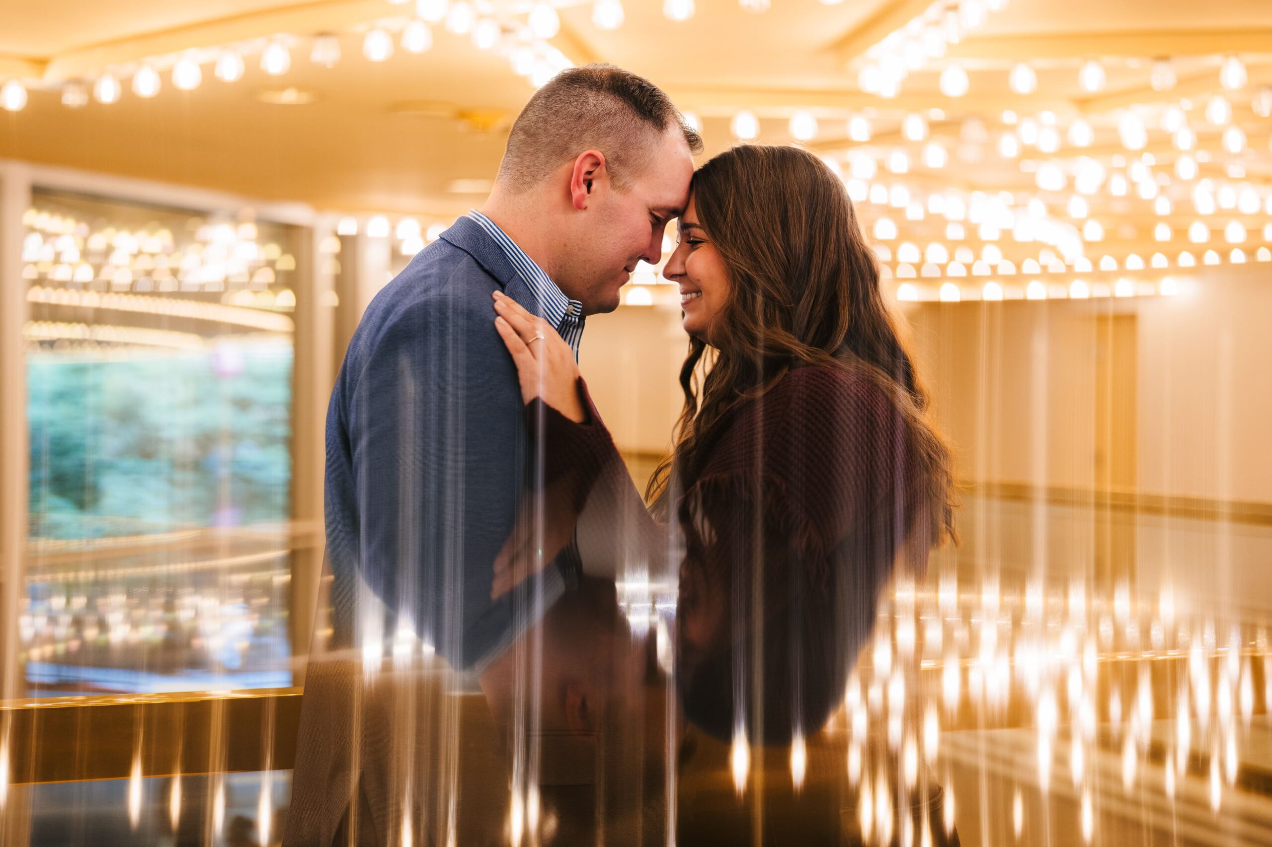 Lovely couple sharing an intimate moment during their engagement at the Flamingo while the best wedding photographer in Las Vegas captures a creative image using the lights and reflections.