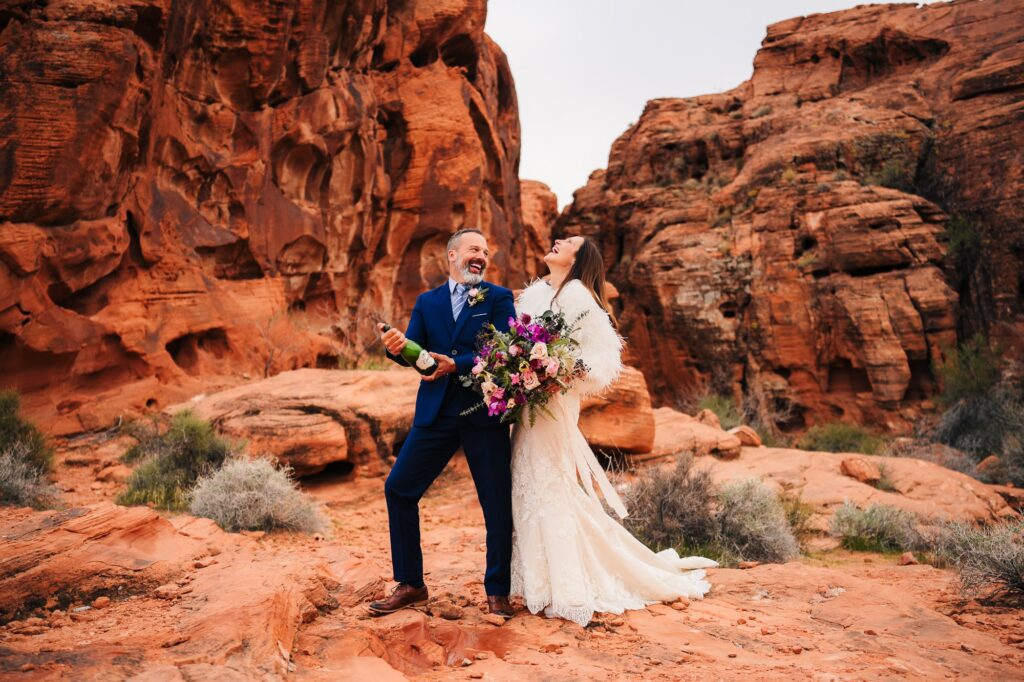 Couple popping a bottle of champagne during their wedding at Valley of FIre