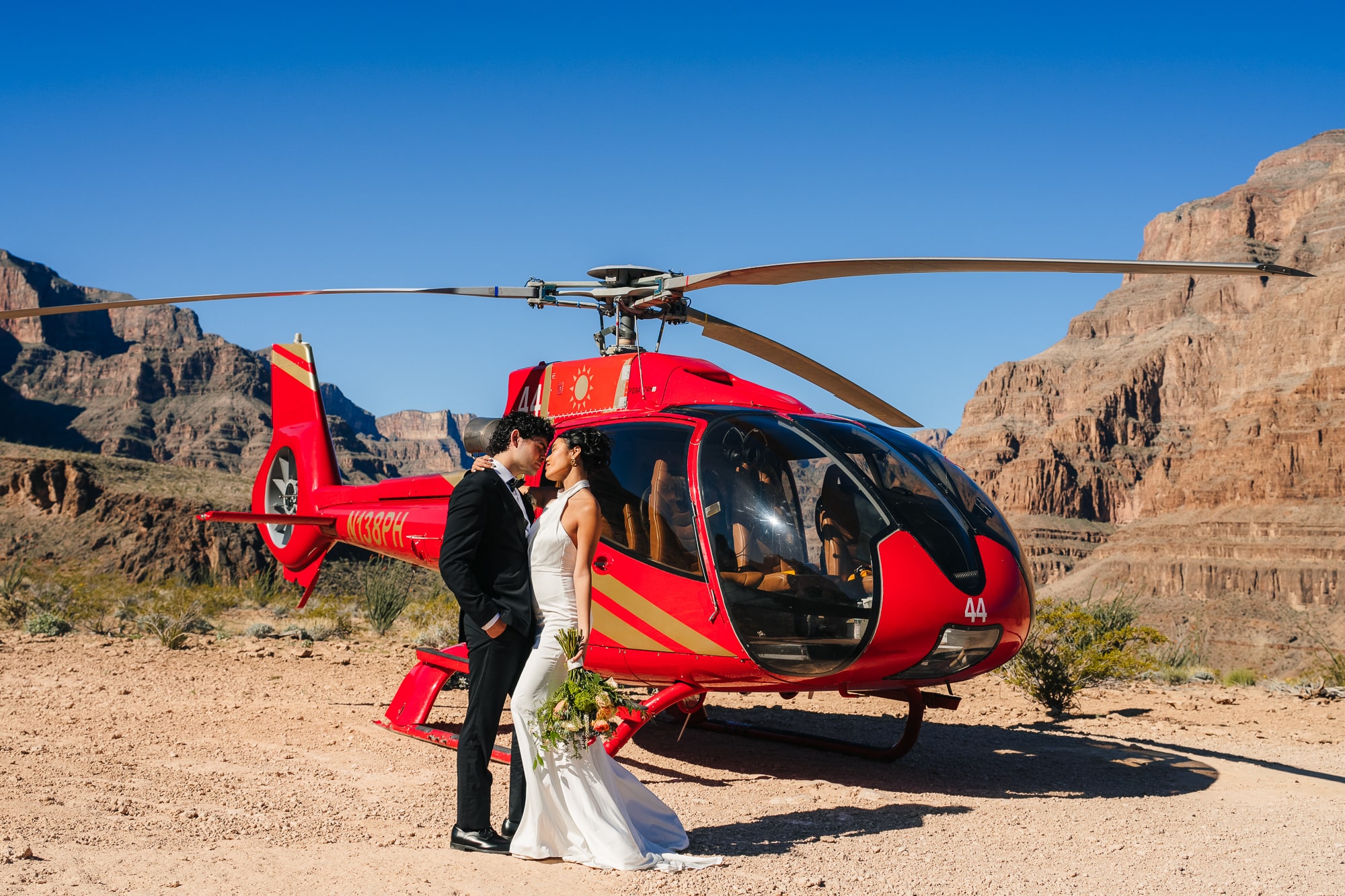Couple sharing an intimate moment during their wedding at the Grand Canyon with a helicopter behind them.