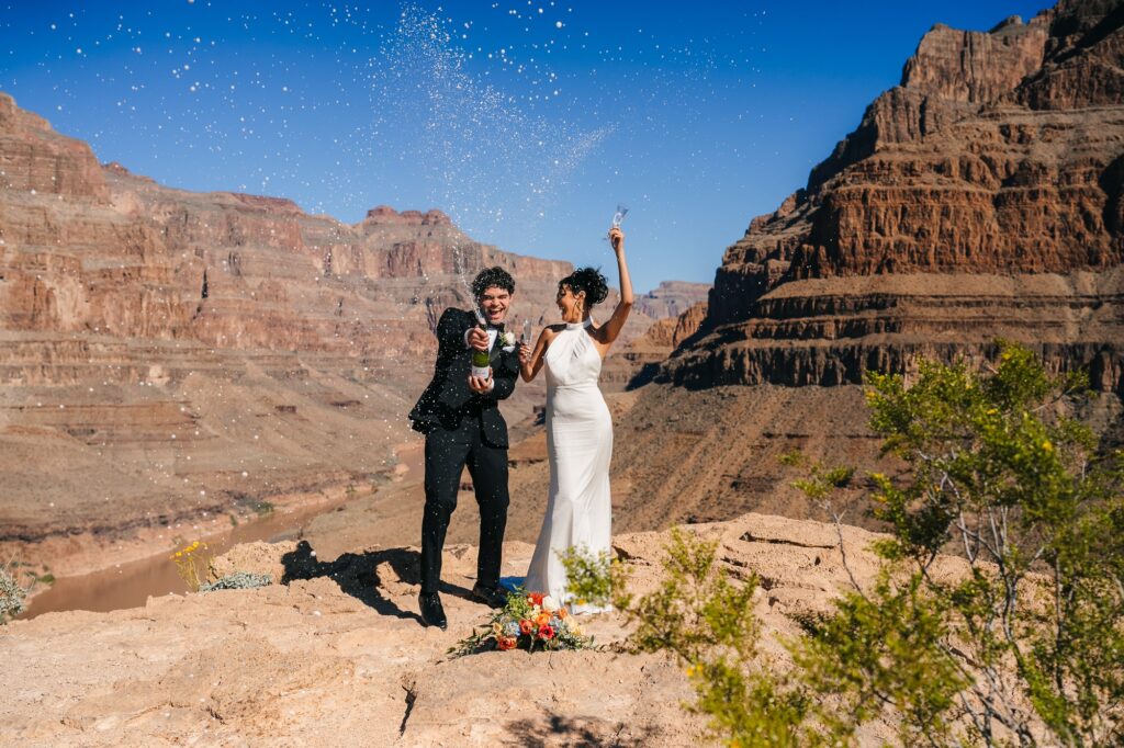 Couple enjoying a champagne pop at Grand Canyon during their helicopter wedding.