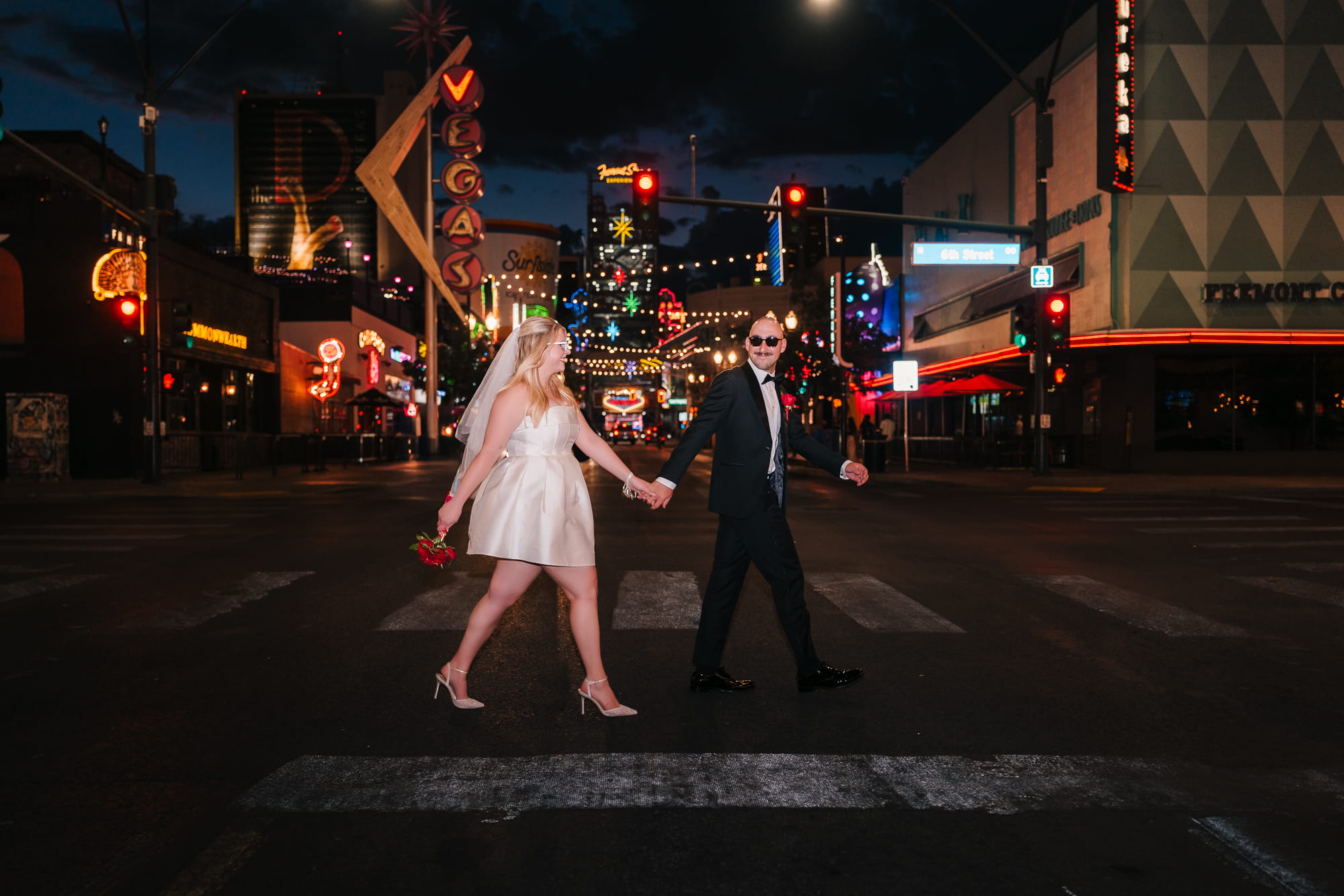 Couple walking across the street during their night time elopement at Fremont Street